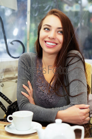 Young joyful lady sitting in the restaurant