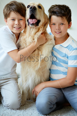 Portrait of happy siblings with their pet looking at camera at home