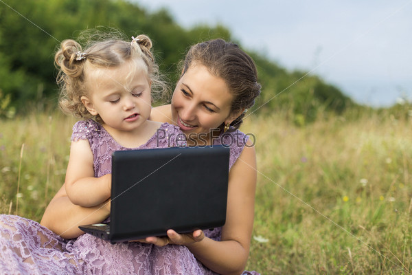 mother and child at a laptop on the nature
