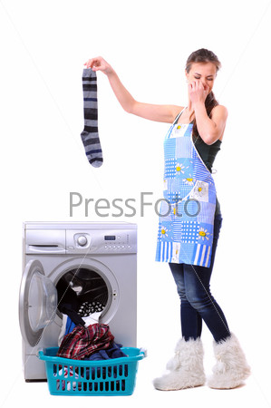 A housewife holding a male sock and her nose next to a washing machine isolated on white