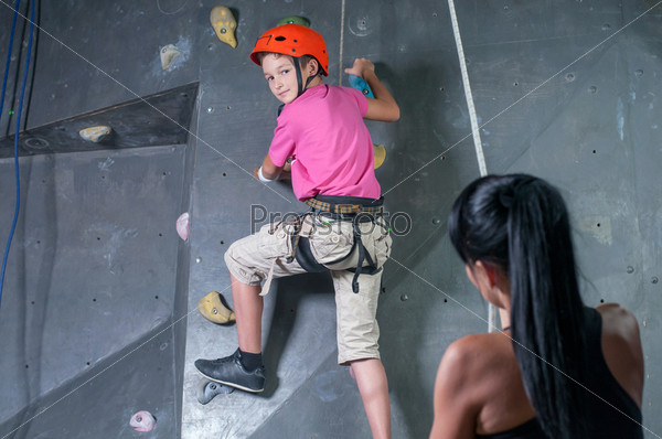 A young boy with his instructor woman. Climbing the wall