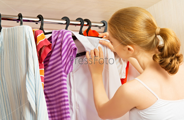 Young woman chooses clothes in the wardrobe closet at home