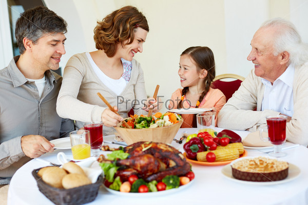 Portrait Of Happy Family Sitting At Festive Table While Having Thanksgiving Dinner