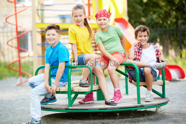 Image of little friends sitting on carousel and looking at camera