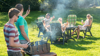 Group of young friends enjoying barbecue in a garden on a sunny afternoon