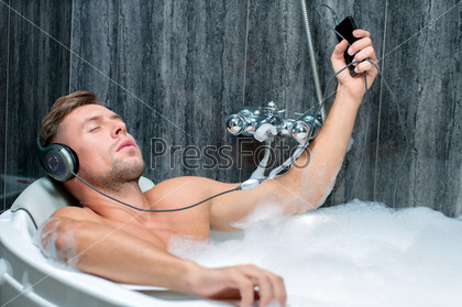 young man taking a bath, listening to music from the player