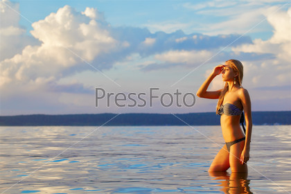 full-length portrait of young beautiful tanned blonde woman in ocean waters
