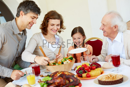 Portrait of happy family sitting at festive table while having Thanksgiving dinner