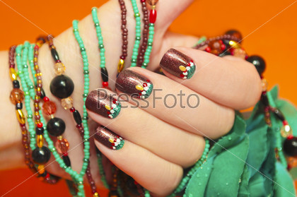 Women\'S Nails Are Covered With Brown Varnish With The Design Of White,Red And Turquoise Points On An Orange Background With A Bracelet Made Of Beads In The Tone Of The Nail.