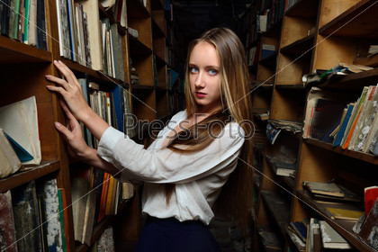 Beautiful woman choosing the book in library.