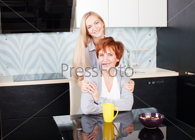 Happy adult woman with daughter on kitchen. Family at home.