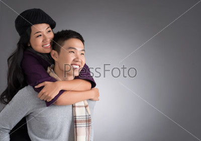 Copy-spaced image of a cheerful young couple piggybacking over a grey background