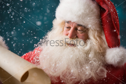 Portrait Of Happy Santa Claus Reading Christmas Letter Outdoors At North Pole At Snowfall