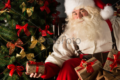 Санта с подарками под елкой в темной комнате
