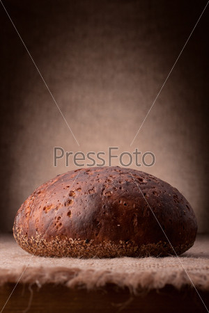 Loaf of rye bread on rustic background