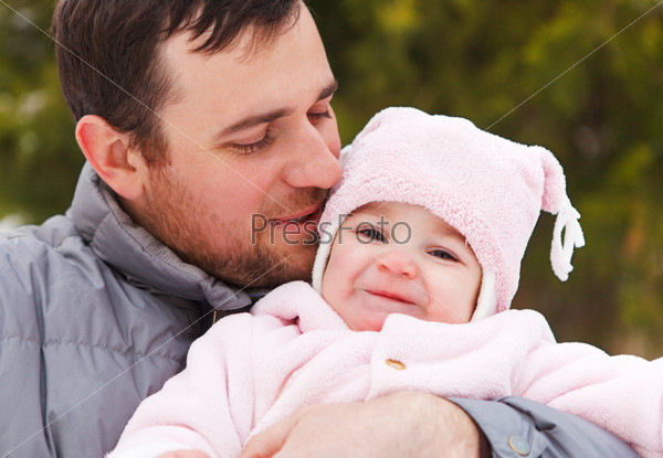 Happy smiling father with one year old baby girl outdoors. Winter time