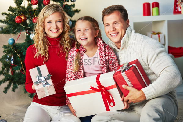 Portrait of happy family with giftboxes looking at camera on Christmas day