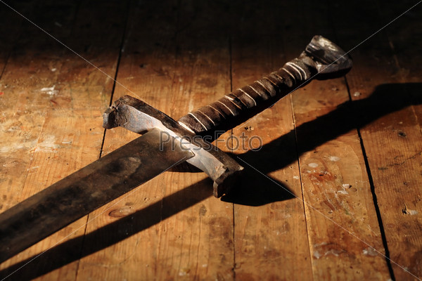 War symbol. Medieval knight sword on dirty wooden surface
