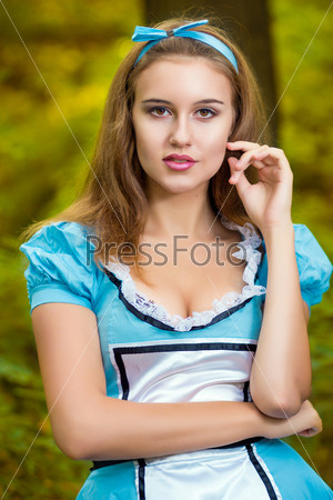 Portrait of a beautiful young girl with long hair on nature in a fabulous costume Alice in Wonderland