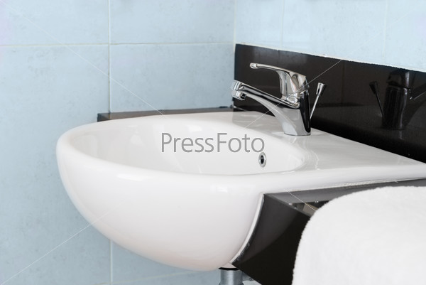 Modern ceramic hand wash basin with chrome water mixer tap in hotel washroom interior