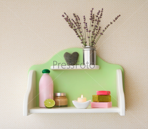 Decorative shelf on the wall with lavender flowers in vase and cosmetics on it