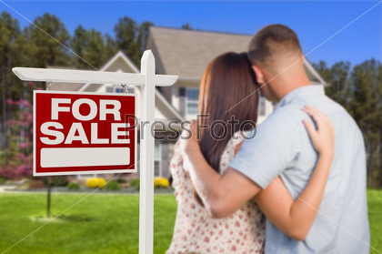 Пара стоит перед домом со знаком о продаже