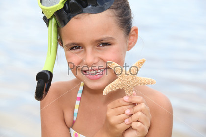 Little girl at the beach holding star fish