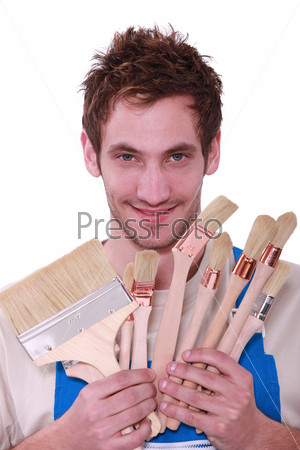 Young man with a selection of decorating paint brushes