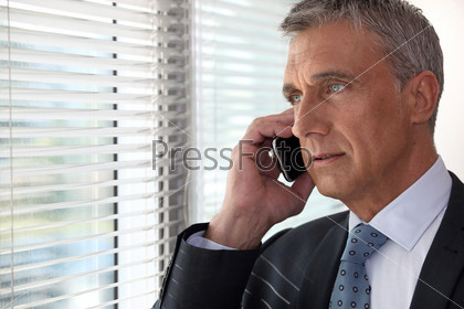 Директор говорит по телефону перед окном