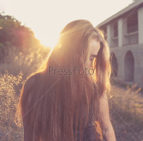 Pretty blond women at autumn sunset. Her face hidden by sand-color hair. Backlit. Square crop shot, stock photo