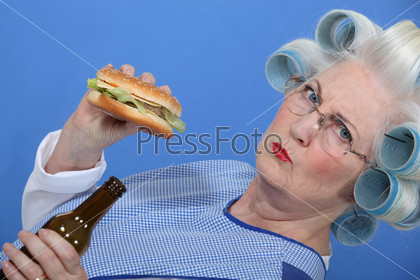An old lady enjoying a burger and a beer.