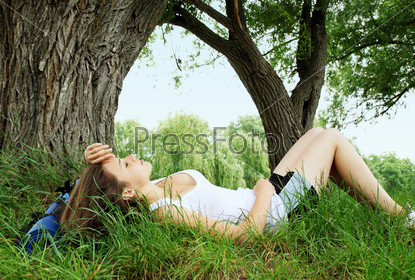Woman with a backpack resting on the bank of the river, stock photo