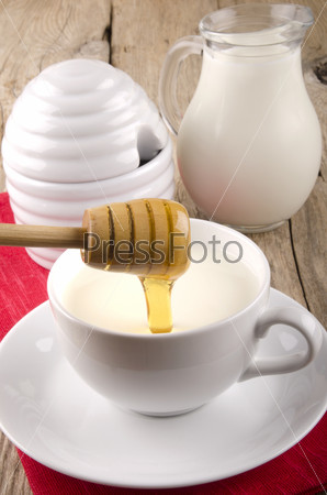 sweet honey flows into a cup with warm milk