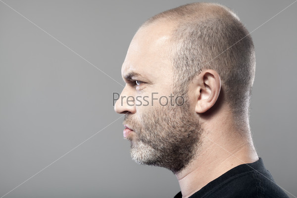 Портрет мрачного мужчины в профиль, изолированный на сером фоне