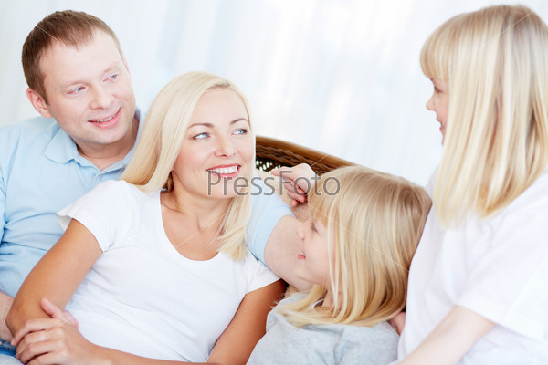 Portrait of happy twin girls and their parents talking at home