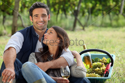 Romantic man and woman picking grapes and drinking wine