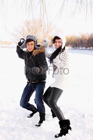 happy couple throwing snowballs in the park