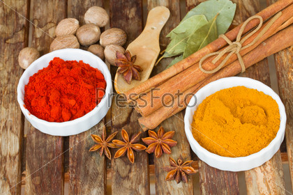 powdered  spices of curry and red pepper with seeds of anise and cinnamon on wooden table