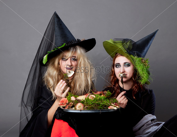 Halloween party - women in costumes of witches dine snakes and mushrooms