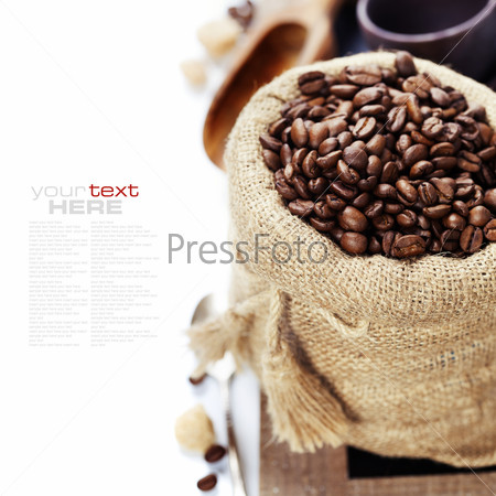 Coffee beans in burlap sack with wooden scoop  over white (with sample text)