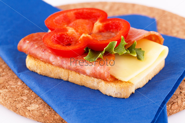 Sandwich on blue napkin on brown round board.