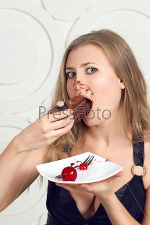 Girl eating cake with his hands, her face stained cream.