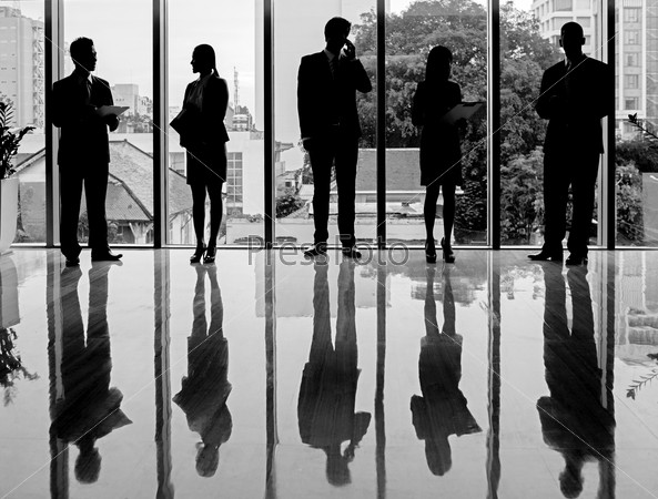 Black-and-white silhouettes of business people standing and working