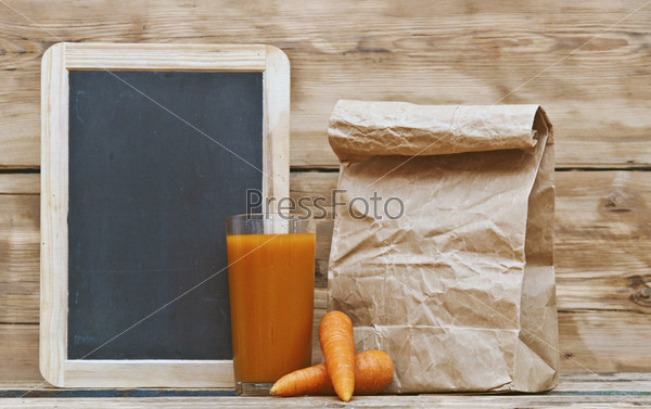 Здоровое питание - морковь и сок с бумажным мешком на досках