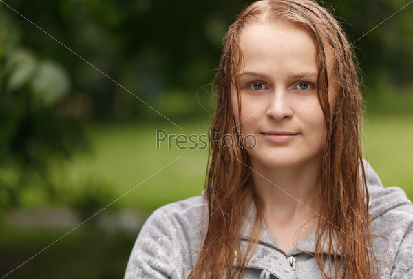Portrait of a girl looking to the photographer in the park after rain with copyspace on left side.