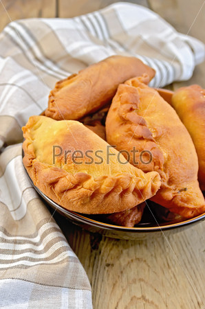 Dish with fried pies, napkin against a wooden board