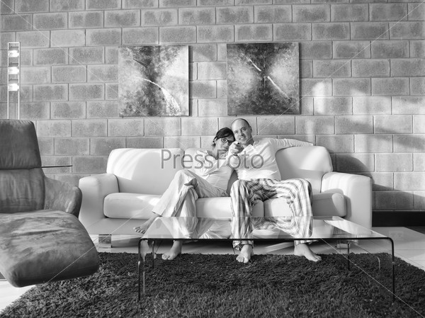 Relaxed young couple watching tv at home in bright living room, stock photo