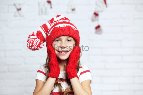 Little fashion girl in fashion Christmas clothes posing over white brick background, full length