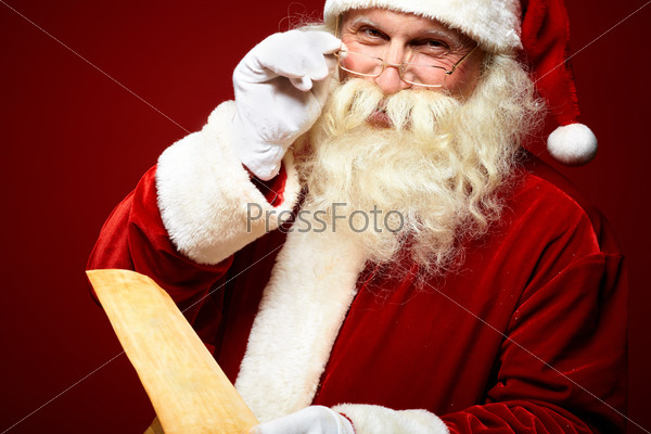 Portrait of happy Santa Claus holding Christmas letter in his hands and looking at camera