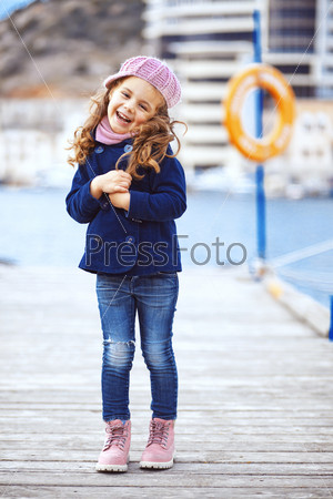 Portrait of 4 years old girl walking on berth near sea in the city, still life photo